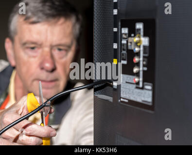 Ältere Menschen schneiden Sie das Kabel auf seinem Kabel-TV-Paket Stockfoto