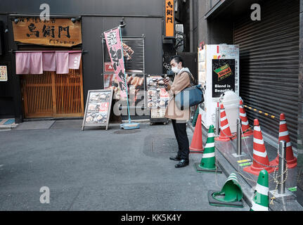 Mann sein Handy bei Backstreet in Tokio prüfen. Stockfoto