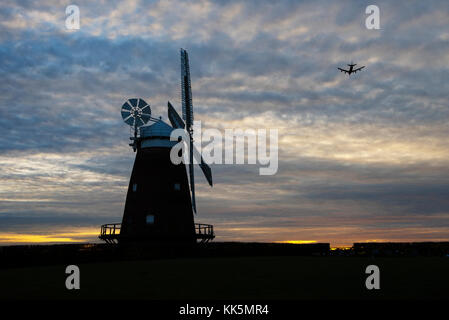 Thaxted Windmühle in der Dämmerung mit Flugzeugen in Land in der Nähe von Stansted Airport kommen. Essex England UK. Nov 2017 Stockfoto