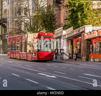 Rote Straßenbahn, die durch die Stadt läuft - Innsbruck Österreich, Europa. städtische Szene Stockfoto