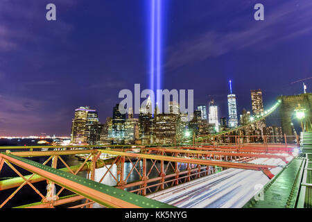 New York City Manhattan Downtown Skyline bei Nacht von der Brooklyn Bridge mit dem Tribute in Light im Speicher des 11. September. Stockfoto