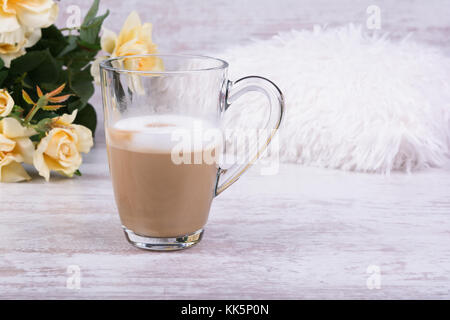 Hot latte Kaffee in clear Cup und schöne gelbe Rosen auf weiß Holz- Hintergrund. Stockfoto