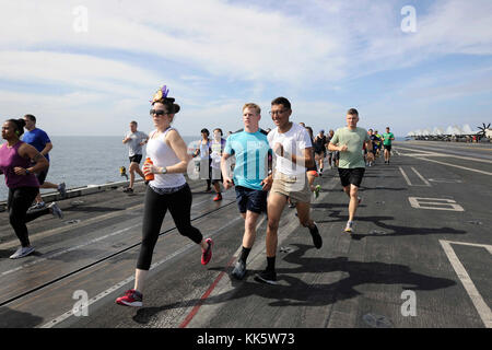 INDISCHER OZEAN (Nov 23, 2017) während des Thanksgiving Turkey Trab 5K an Bord des Flugzeugträgers USS Theodore Roosevelt (CVN 71) laufen Matrosen und Marines über das Flugdeck. Theodore Roosevelt wird zur Unterstützung von Seeverkehrssicherheitsoperationen und der Zusammenarbeit im Bereich der Theatersicherheit eingesetzt. (USA Navy Foto von Mass Communication Specialist 1st Class Michael Russell/veröffentlicht) Stockfoto