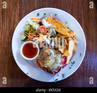 Rot gefüllte Paprika Pfeffer mit Käse, Kartoffelecken, Soße und frischen Salaten der Saison Stockfoto