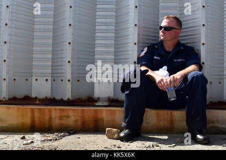 U.S. Coast Guard Petty Officer 1st Class Ryan Swartz, ein Maschinen Techniker am nationalen Streik's Force Golf Strike Team und ein Mitglied der Küstenwache, nimmt einen Bruch nach dem Vermessen vertriebenen Schiffe in Fajardo, Puerto Rico, 6. November 2013. Mitglieder der Nationalen Strike Force spielen eine wesentliche Rolle in der Reaktion der Küstenwache auf Hurrikan Maria. U.S. Coast Guard Foto von Petty Officer 2. Klasse Ali Flockerzi. Stockfoto