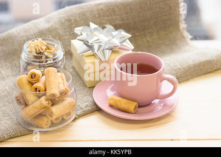 Eine festliche noch Leben mit einem rosa Tasse Tee, Plätzchen, trockene Blumen und einem Geschenkkarton Stockfoto