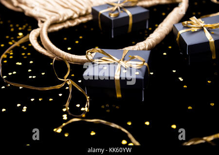 Schwarz Geschenksets mit Gold Ribbon Pop aus goldenen Tasche auf/ Hintergrund Stockfoto