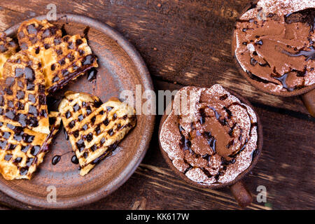 Belgische herzförmige Waffel mit heißer Schokolade mit Marshmallows auf hölzernen Hintergrund Stockfoto