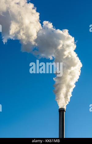 Eine Wolke von weißem Rauch die Flucht aus einem metallischen Schornstein gegen den tiefblauen Himmel. Stockfoto