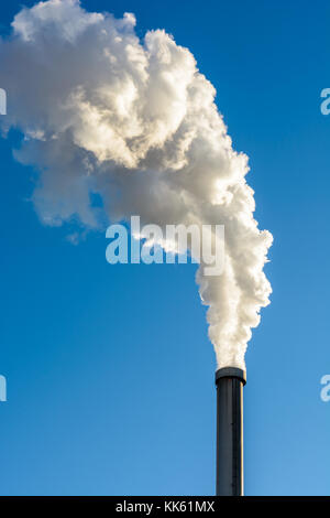 Eine metallische Schornstein heraus zu spucken. Eine dicke Wolke von weißem Rauch gegen den tiefblauen Himmel. Stockfoto