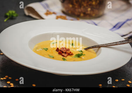 Rote Linsensuppe mit gegrillten Würstchen in Weiß Platte auf dunklem Stein Stockfoto