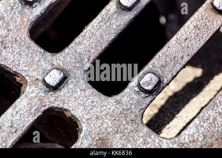 Nahaufnahme der Metallgitter von Kanalisation, Muster der quadratischen Gitters, Mannloch Kanaldeckel in Beton. Stockfoto