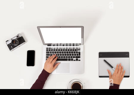 Saubere und moderne Arbeitsplatz. notebook, Kaffee, Graphic Tablet, Telefon, Kamera und Aufgabenliste und weibliche Hände von oben. Stockfoto