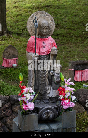 Nara/Japan, 30. Mai 2017: Traditionelle Stein gemeißelt jizo mit roten Rock mit Blumen geehrt und geachtet Stockfoto