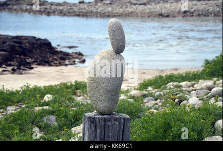 Kleiner Stein ausgeglichen auf großen Stein auf einem alten Fencepost auf der Insel Bryher, Isles of Scilly, Cornwall, Großbritannien. Stockfoto