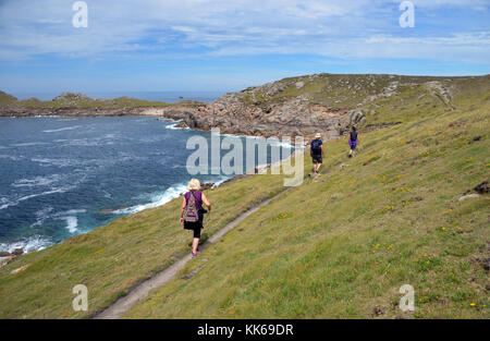 Drei Wanderer auf Coastal Path in der Hölle Bay zu Shipman Kopf auf bryher Insel in der Scilly-inseln, Cornwall, Großbritannien, UK. Stockfoto