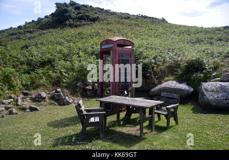 Rote Telefonzelle und Tisch & Stühle außerhalb der Fraggle Rock Bar & Coffee Shop in Bryher Insel in der Scilly-inseln, Cornwall, Großbritannien, UK. Stockfoto