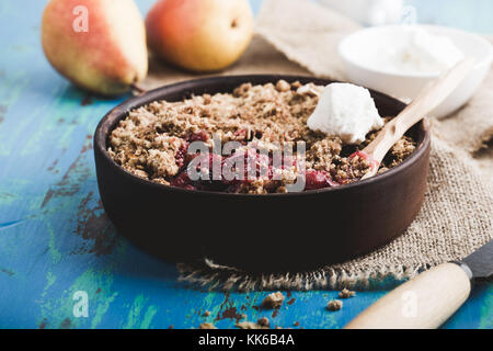 Birne und Berry zerfällt, serviert mit Sahne im rustikalen Keramik Schüssel Stockfoto