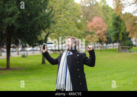 Hispanic Mann chatten mit Freundin auf dem Smartphone im Park. Stockfoto