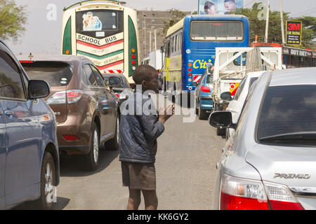 Eine junge kenianische Junge auf der Straße Passanten im Verkehr an einer viel befahrenen Straße, Kenia klemmt Betteln, Ostafrika Stockfoto