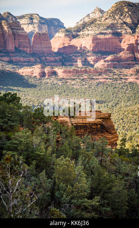 Eine einsame Frau Wanderer auf einem Felsvorsprung mit Blick auf den Red Rock Canyons außerhalb von Sedona, Arizona, USA. Stockfoto