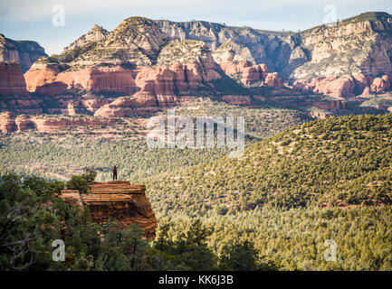 Eine einsame Frau Wanderer auf einem Felsvorsprung mit Blick auf den Red Rock Canyons außerhalb von Sedona, Arizona, USA. Stockfoto