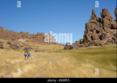 Mann, der auf einem Esel in einer verlassenen Landschaft reitet Stockfoto