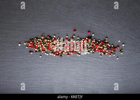 Farbige Paprika auf der Schiefertafel verstreut, oben viewcolored Paprika auf der Schiefertafel verstreut, Ansicht von oben Stockfoto