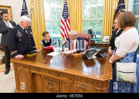 US-Präsident Donald Trump schreibt eine Notiz für den Christen, den Enkel der Ehrenmedaille, der den pensionierten US-Army Captain Gary M. Rose verließ, während eines Familienbesuchs im Oval Office des Weißen Hauses am 23. Oktober 2017 in Washington, DC. Stockfoto