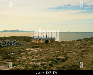 Moderne steinigen Familienhaus auf der Feder am Meer, Norwegen Insel. Ein traditionelles Steinhaus mit einem wunderschönen Blick auf das Meer Bucht. felsige Landschaft mit Stockfoto