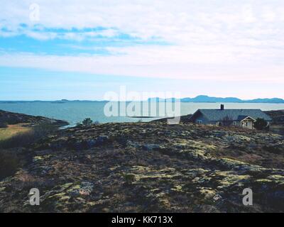 Moderne steinigen Familienhaus auf der Feder am Meer, Norwegen Insel. Ein traditionelles Steinhaus mit einem wunderschönen Blick auf das Meer Bucht. felsige Landschaft mit Stockfoto