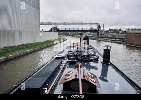 Sie steuern ein Schmalboot durch Chemiewerke in Northwich am Trent- und Mersey-Kanal Stockfoto