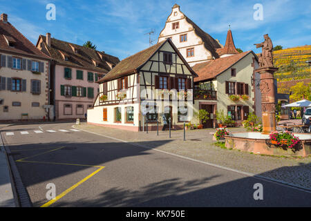 Fachwerkhäuser mit Brunnen und Blick auf die Weinberge, Dorf Andlau, Ausläufer der Vogesen, auf der Weinstraße des Elsass, Frankreich Stockfoto