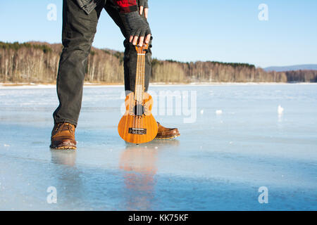 Mann mit ukelele stehend auf einem zugefrorenen See Stockfoto