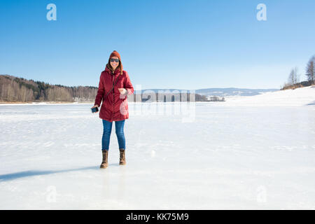 Glückliches Mädchen, stehend auf einem zugefrorenen See. Winter Spaß Stockfoto