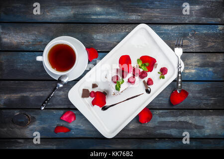 Köstliche pavlova Kuchen mit einer Tasse Kaffee. frische Himbeeren auf einer weißen Platte mit Rosenblättern. top anzeigen. schönen hölzernen Hintergrund. Stockfoto