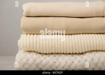 Stapel aus Gewirken Kleider (Pullover, Schals, Pullover), Weiß und Beige. Selektive konzentrieren. Stockfoto