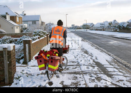 Postbote, die an einem verschneiten Tag Fahrrad fahren. Foto von Nikki Attree Stockfoto