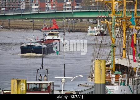 Bremen, Deutschland - 23. November 2017 - Binnenschiff über eine Brücke über die Weser mit Wohngebäuden im Hintergrund und vertäut Stockfoto