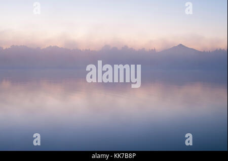 Mount Pichuck Sonnenaufgang mit Nebel und Bäume entlang weit Shoreline mit Reflexionen Stockfoto