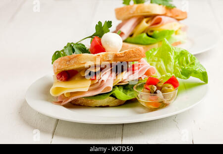 Foto von leckeren Toast gefüllt mit Käse und Schinken mit Salat und Petersilie Stockfoto