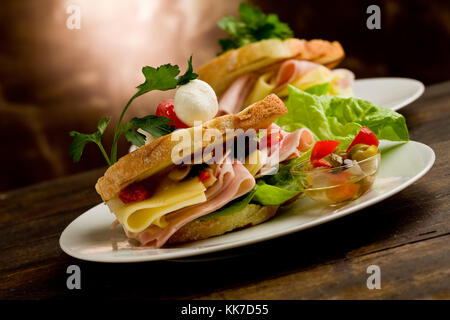 Foto von leckeren Toast gefüllt mit Käse und Schinken mit Salat und Petersilie Stockfoto