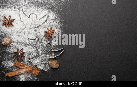 Backen Weihnachtsplätzchen - Ausstechformen, Zimt, Anis, Haselnüsse auf schwarzem Hintergrund Stockfoto