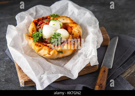 Torte im orientalischen Stil. Blätterteig mit Tomate und Mozzarella. dunklen Hintergrund. vegetarische Kost Stockfoto