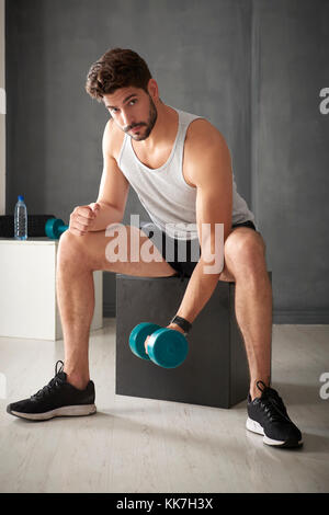 Schuss ein junger sportlicher Mann, Arbeit mit Gewichten in der Turnhalle. Stockfoto