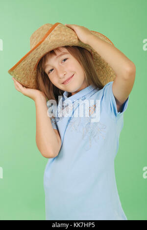 Junges Mädchen mit hellen Haaren Holding einen Strohhut in der Hand auf grünem Hintergrund isoliert Stockfoto