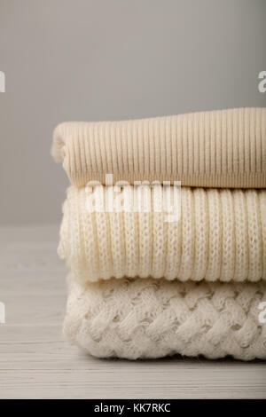 Stapel aus Gewirken Kleider (Pullover, Schals, Pullover), Weiß und Beige. Selektive konzentrieren. Stockfoto