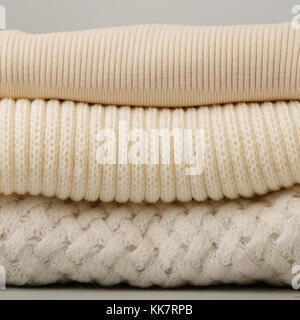 Stapel aus Gewirken Kleider (Pullover, Schals, Pullover), Weiß und Beige. Selektive konzentrieren. Stockfoto