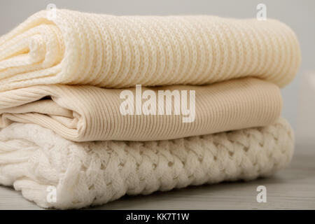 Stapel aus Gewirken Kleider (Pullover, Schals, Pullover), Weiß und Beige. Selektive konzentrieren. Stockfoto
