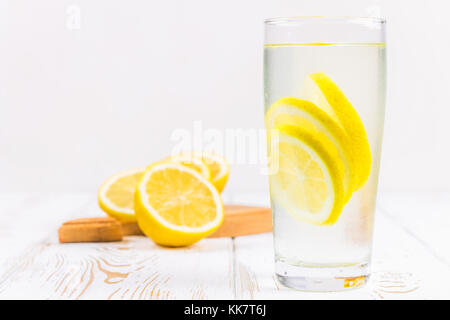 Ein Becherglas und einen Krug kalten Limonade auf einem weißen Hintergrund Holz umgeben von Zitronen Stockfoto